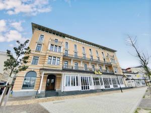 ein großes gelbes Gebäude mit weißen Fenstern auf einer Straße in der Unterkunft Berringer, Knurrhahn, direkt an der Promenade in Warnemünde