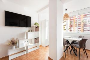 Biały salon ze stołem i telewizorem w obiekcie Apartamento Lucía w mieście Torre del Mar