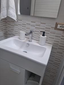 un lavandino bianco del bagno con due tazze sopra di Machi House a Scafati