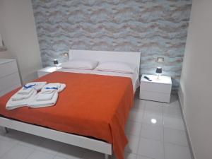 una camera da letto con un letto con coperta arancione e due comodini di Machi House a Scafati