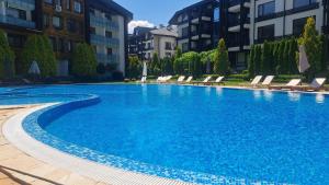 a large blue swimming pool with chairs and buildings at Pirin Views Aspen A337 in Razlog