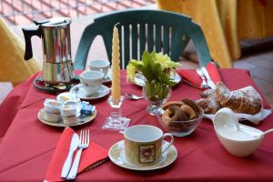 a table with a red table cloth with food and cups at Casabella rooms in Riposto