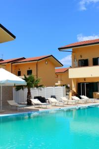 a pool with chairs and umbrellas next to a building at Conca Degli Dei in Paestum