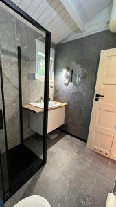 a bathroom with a shower and a sink and a mirror at Carpinus I domek nad jeziorem in Łętowo