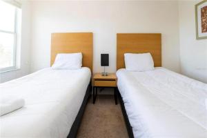 two twin beds in a room with a night stand at 3065 YL - Cozy 2BR Townhome - Encantada in Kissimmee