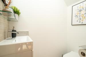a white bathroom with a sink and a picture on the wall at Large 4BR Contractor-Friendly House - Sleeps 10 - Free parking - North London in Enfield +66 photos