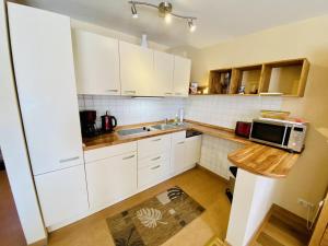 a kitchen with white cabinets and a sink and a microwave at Ferienhaus Ostseeperle in Warnemünde