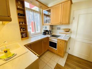 a kitchen with wooden cabinets and a sink and a window at Ostseeliebe, direkt an der Promenade in Warnemünde