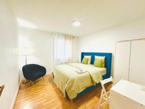 a bedroom with a bed with a blue headboard and a chair at Holiday Apartment 03 in Stains