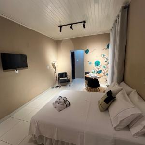 a bedroom with a large white bed and a tv at Cantim d' Casa in Catas Altas