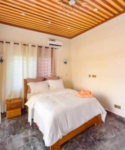 a bedroom with a large bed with a wooden ceiling at Résidence LH in Brazzaville +17 photos