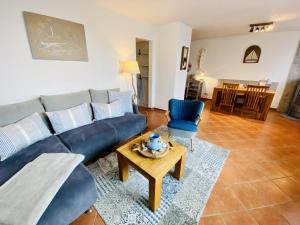 un salon avec un canapé bleu et une table dans l'établissement Ferienhaus Strandkoje, à Warnemünde