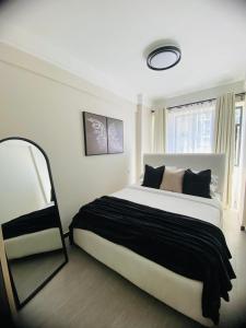 a bedroom with a large bed and a mirror at Cozy 1BR Hideout Kilimani in Nairobi