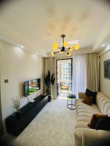 a living room with a couch and a tv at Cozy 1BR Hideout Kilimani in Nairobi