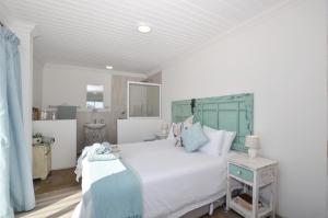 a bedroom with a large white bed with a blue headboard at Hemelstoep Pool View in Yzerfontein