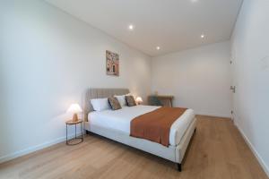 a white bedroom with a bed and two lamps at Auréa House - Luxury Ocean View in Feteiras