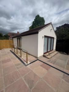 a small white building with a fence on a patio at Portbridge Nest in Chew Magna