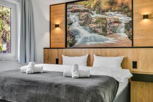 a bedroom with a bed with a painting on the wall at STANMA Lodge Braunlage - Naturpartments am Fluss mit Sauna und Bergblick in Braunlage +101 photos