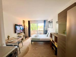 a bedroom with a bed and a desk and a television at L'Estival, Royan in Royan