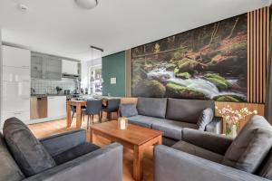 a living room with a couch and a kitchen at STANMA Lodge Braunlage - Naturpartments am Fluss mit Sauna und Bergblick in Braunlage