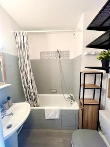 a bathroom with a tub and a toilet and a sink at L'Estival, Royan in Royan