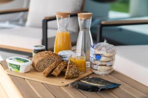 a wooden tray with bread and orange juice and a bottle at Auréa House - 4BR Azores Villa with Ocean View, BBQ & AC in Feteiras
