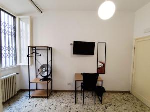 a room with a desk and a television on a wall at Verdi Central Rooms in Florence