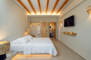 伊奥斯乔拉Sohoro Olive的卧室里有一张白色的床和一台电视