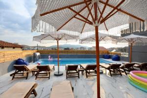 een patio met stoelen en parasols naast een zwembad bij Vila Naço Ksamil in Ksamil