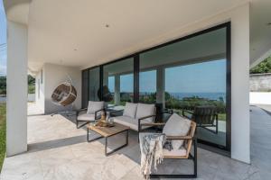 a living room with glass walls and a patio at Auréa House - Luxury Ocean View in Feteiras