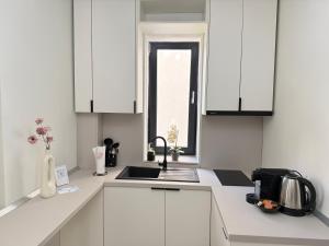 eine Küche mit weißen Schränken und einer Spüle und einem Fenster in der Unterkunft COZY Aparthotel - Luxury Studios # Brasov in Braşov