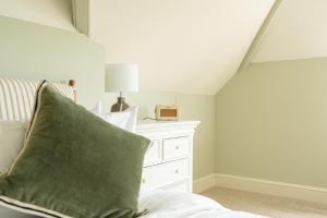 a bed with a green pillow next to a white dresser at The Ox Pub & Rooms in Poole +16 photos