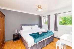 a bedroom with a bed and two windows at Beautiful 3 Bedroom Home with Parking & Garden in Colchester