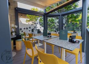 a restaurant with tables and yellow chairs and windows at Hotel La Rocca in San Marino
