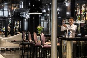 a man standing at a bar holding a glass at Maison Albar - Le Diamond in Paris +72 photos