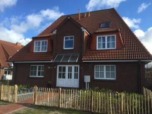 诺德奈Apartment Emsköpken的棕色砖屋,设有木栅栏