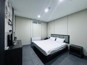 um quarto com uma grande cama branca e uma televisão em Lofty Hotel em Ulaanbaatar