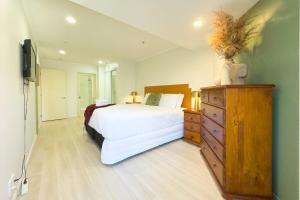 ein Schlafzimmer mit einem Bett, einer Kommode und einem Fernseher in der Unterkunft Two bedrooms Condo with Skytower View in Auckland
