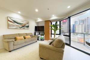 ein Wohnzimmer mit zwei Sofas und einem Fernseher in der Unterkunft Two bedrooms Condo with Skytower View in Auckland