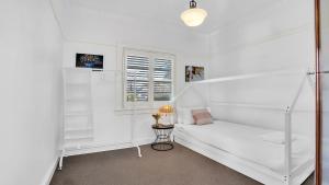 a white room with a bed and a window at Kookaburra Cottage in Bowral