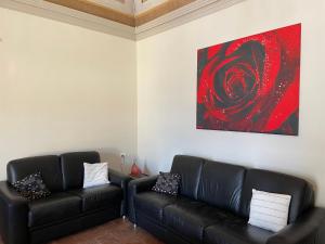 a living room with two black leather couches and a painting at Once upon a time in Domaso