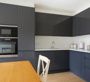 a kitchen with blue cabinets and a wooden table at Elegant 2 Bed Flat with Balcony in Finchley in Hendon