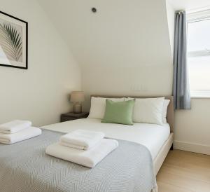 a white bed with two white towels on it at Elegant Flat with Balcony in Finchley in Hendon