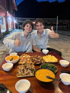 two men giving thumbs up at a table of food at Mùa Pửi Lô lô homestay in Mèo Vạc