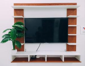 a flat screen tv on a white wall at Anand Nivas Homestay 10 Mins from Mandir in Deoghar