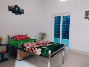 a bedroom with a bed with a green blanket and a window at Anand Nivas Homestay 10 Mins from Mandir in Deoghar