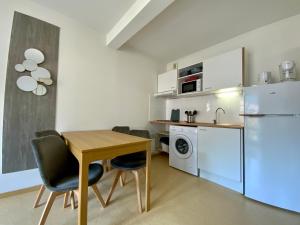 a small kitchen with a table and a refrigerator at Les Naïades G32 - 2 chambres pour 5 personnes ! in Avène