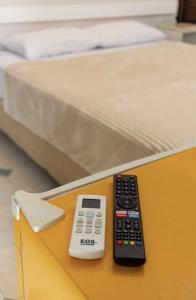 two remote controls sitting on a table next to a bed at Pousada Pôr Do Sol - Ilha do Mel - Nova Brasília in Paranaguá
