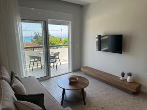 a living room with a couch and a tv and a table at Liofoto Sea View Apartments in Stalida