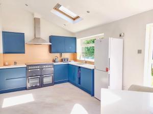 a kitchen with blue cabinets and a white refrigerator at 4Bedroom Modern Bicester Villa, WIFI, Parking, Garden, Minutes walk to Bicester Village in Bicester